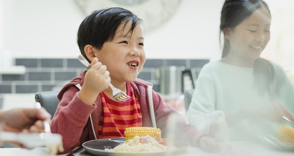 Kinder beim gemeinsamen Essen am Tisch.