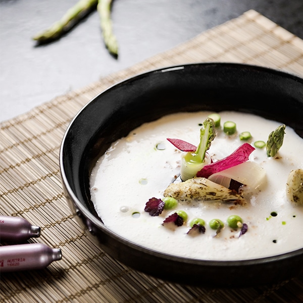 Spargelcremesuppe, aufwändig mit Spargelstückchen angerichtet, zubereitet mit den Whippern von iSi.